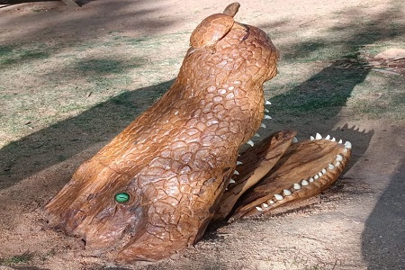 Una escultura de madera simula un cocodrilo que sale del agua en Zamora